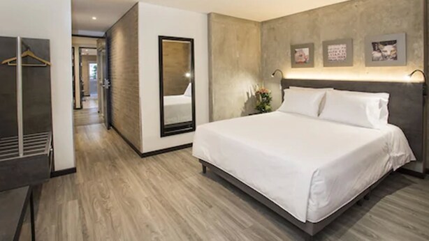 A modern hotel room with a large bed, a wardrobe, and a mirror. - Hotel Quinta Norte Chipichape Cali (Cali)