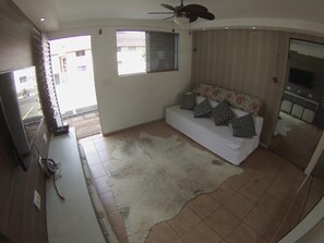 Ein Schlafzimmer mit Bett, Deckenventilator, Fernseher und Fenster.