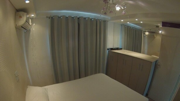 Ein Schlafzimmer mit Bett, Vorhängen, einem Kleiderschrank und einem Spiegel.