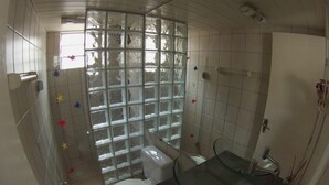 Ein Badezimmer mit Glastrennwand, Toilette, Waschbecken und Duschbereich.