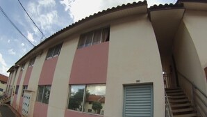 Ein zweistöckiges Gebäude mit einer rosa-weißen Fassade, einer blauen Tür und einer Treppe, die zum Obergeschoss führt.