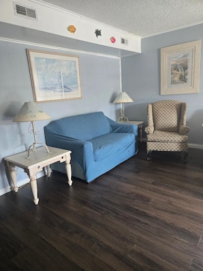 A room with a blue sofa, two lamps, a patterned armchair, and two framed pictures on the wall. - Great Location for your vacation.  Very Pet Friendly!. Close to Boardwalk/Beach. (Ocean City)