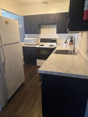 A compact kitchen with a refrigerator, microwave, stove, sink, and dark cabinets. - Great Location for your vacation.  Very Pet Friendly!. Close to Boardwalk/Beach. (Ocean City)