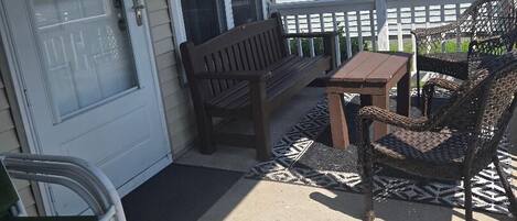 Un patio techado con una puerta, un banco, una mesa y sillas de mimbre.