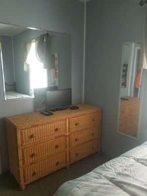 A bedroom with a bed, a dresser, a television, and a mirror.