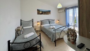 Une chambre avec deux lits, une table de chevet avec une lampe, un tableau au mur et une fenêtre avec des rideaux.