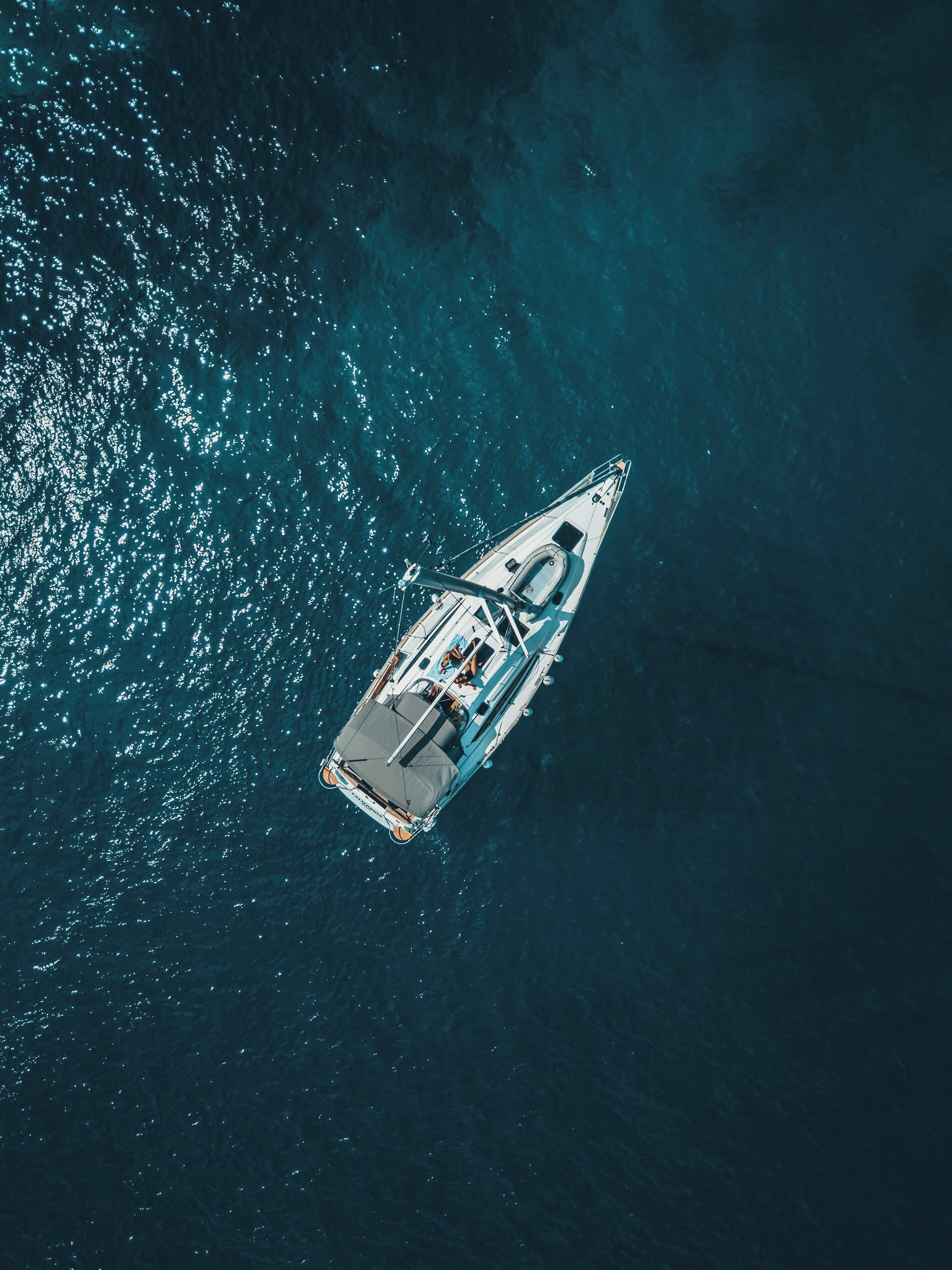 An aerial view of a yacht with a cabin, deck, and a small boat docked at the stern.