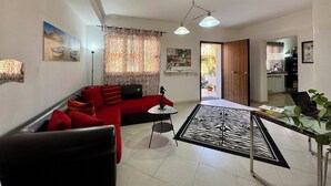 Un salon moderne avec un canapé rouge, une table basse en verre et un tapis à motifs zébrés.