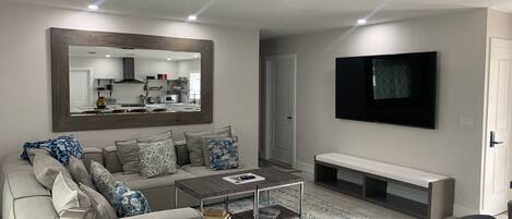 A modern living room with a sofa, coffee table, and a TV mounted on the wall.