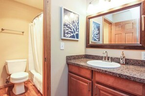 Ein Badezimmer mit Toilette, Dusche, Waschbecken und Holzschränken.