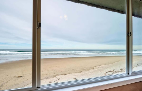 Enjoy the serene ocean views from this room's large windows overlooking the sandy beach.