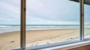 A view of a beach through a window with a clear sky. - Beautiful Oceanfront Suite - Pool and Sauna - Second Floor - Sleeps 4! (Lincoln City)