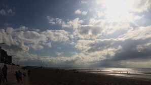 A beach with a wide promenade, a sea view, and a cloudy sky. - Charming two-room refurbished 50m from the sea (Houlgate)