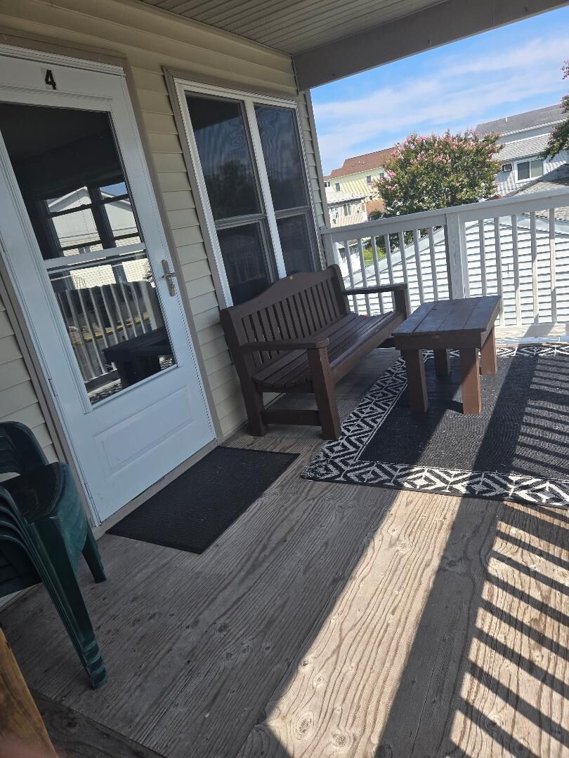 Eine überdachte Veranda mit Bank und Tisch, eine Tür mit Fenster sowie ein gemustertes Teppich.