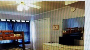 Una habitación con literas, cómoda, espejo y ventilador de techo.