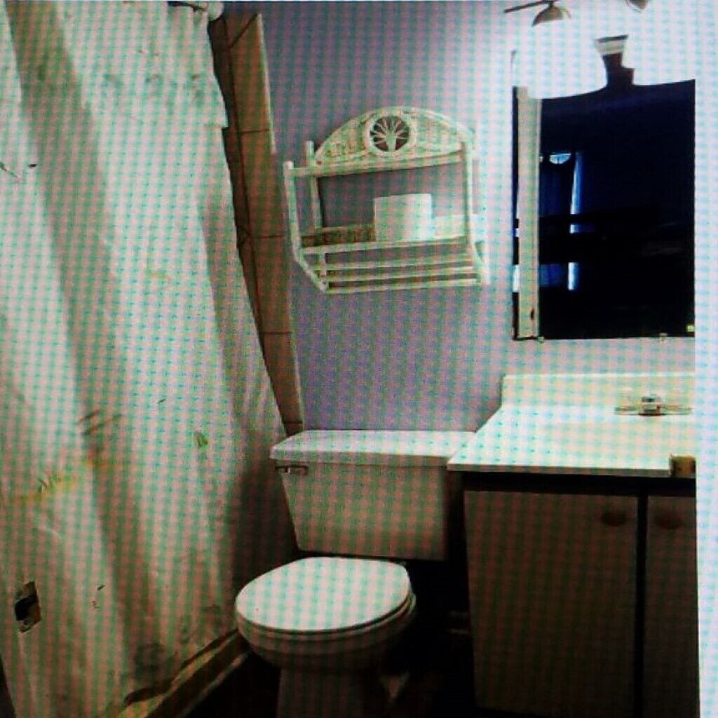 Une petite salle de bain compacte, équipée de toilettes, d’un lavabo et d’un miroir.