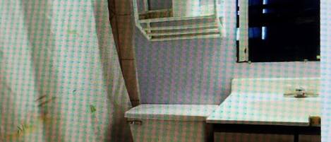 Une petite salle de bain compacte, équipée de toilettes, d’un lavabo et d’un miroir.