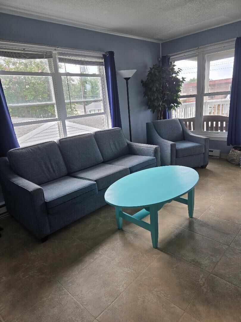 A living room with a sofa, armchair, and round table.