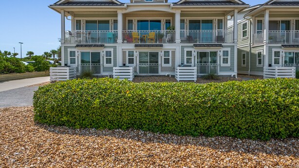 A multi-story residential building with balconies, large windows, and a well-maintained garden. - Ocean View Townhome across from beautiful Amelia Island Beach (Fernandina Beach)