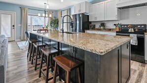 Una cocina moderna con una isla grande, electrodomésticos de acero inoxidable y una zona de asientos con taburetes de bar.