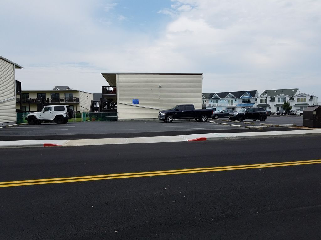 A parking lot with several vehicles, including a white SUV and a black pickup truck.