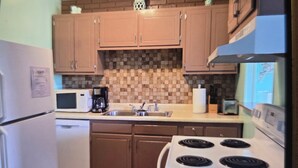 A compact kitchen with wooden cabinets, a microwave, a stove, and a sink. - Great Location for your vacation.  Within walking distance to beach, restaurants (Ocean City)