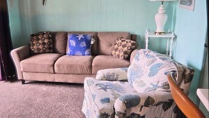 A living room with a sofa, a patterned armchair, a lamp, and a wall-mounted fish. - Great Location for your vacation.  Within walking distance to beach, restaurants (Ocean City)