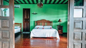 Habitació amb llit de fusta, parets verdes i un lampadari.
