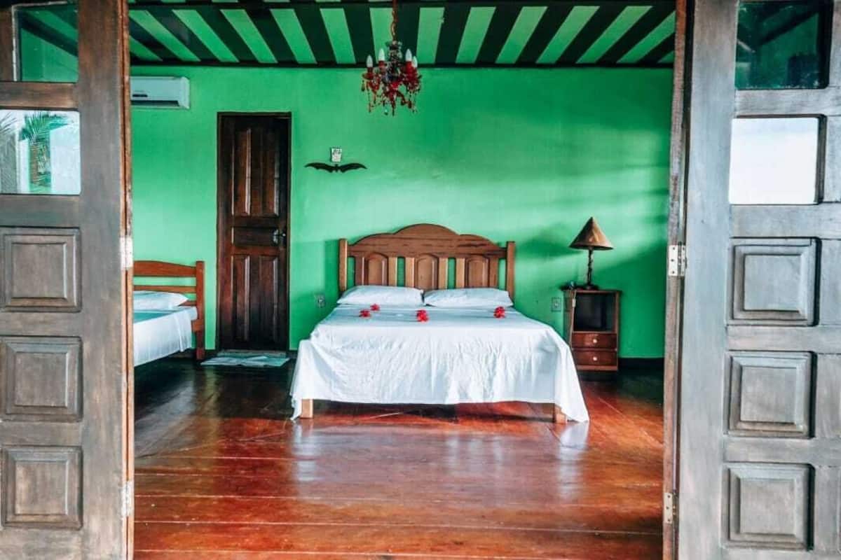 A room with a wooden bed, green walls, and a chandelier.