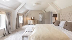 Une chambre avec un grand lit, une commode, une coiffeuse et un dressing.