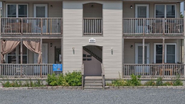 Un motel à deux étages, portant le numéro 320, doté de balcons et d’un escalier visible.