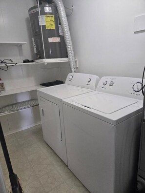 A laundry room with a large water heater, two washing machines, and a shelf with a white cabinet. - Great Location for your vacation.  Very Pet Friendly!. Close to Boardwalk/Beach. (Ocean City)