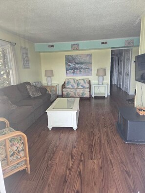 A living room with a sofa, a coffee table, a patterned armchair, and a television. - Great Location for your vacation.  Very Pet Friendly!. Close to Boardwalk/Beach. (Ocean City)