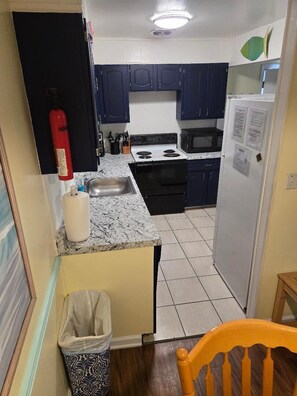 A compact kitchen with dark blue cabinets, a stainless steel sink, a gas stove, and a microwave. - Great Location for your vacation.  Very Pet Friendly!. Close to Boardwalk/Beach. (Ocean City)