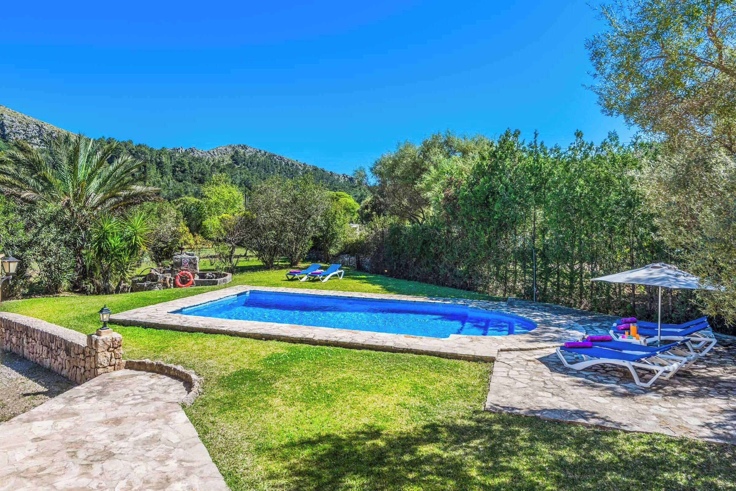A swimming pool with lounge chairs and a stone pathway.
