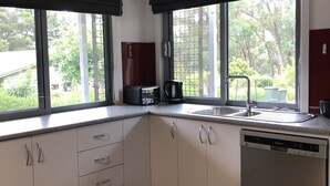 A modern kitchen with two windows, a dishwasher, and a coffee maker.