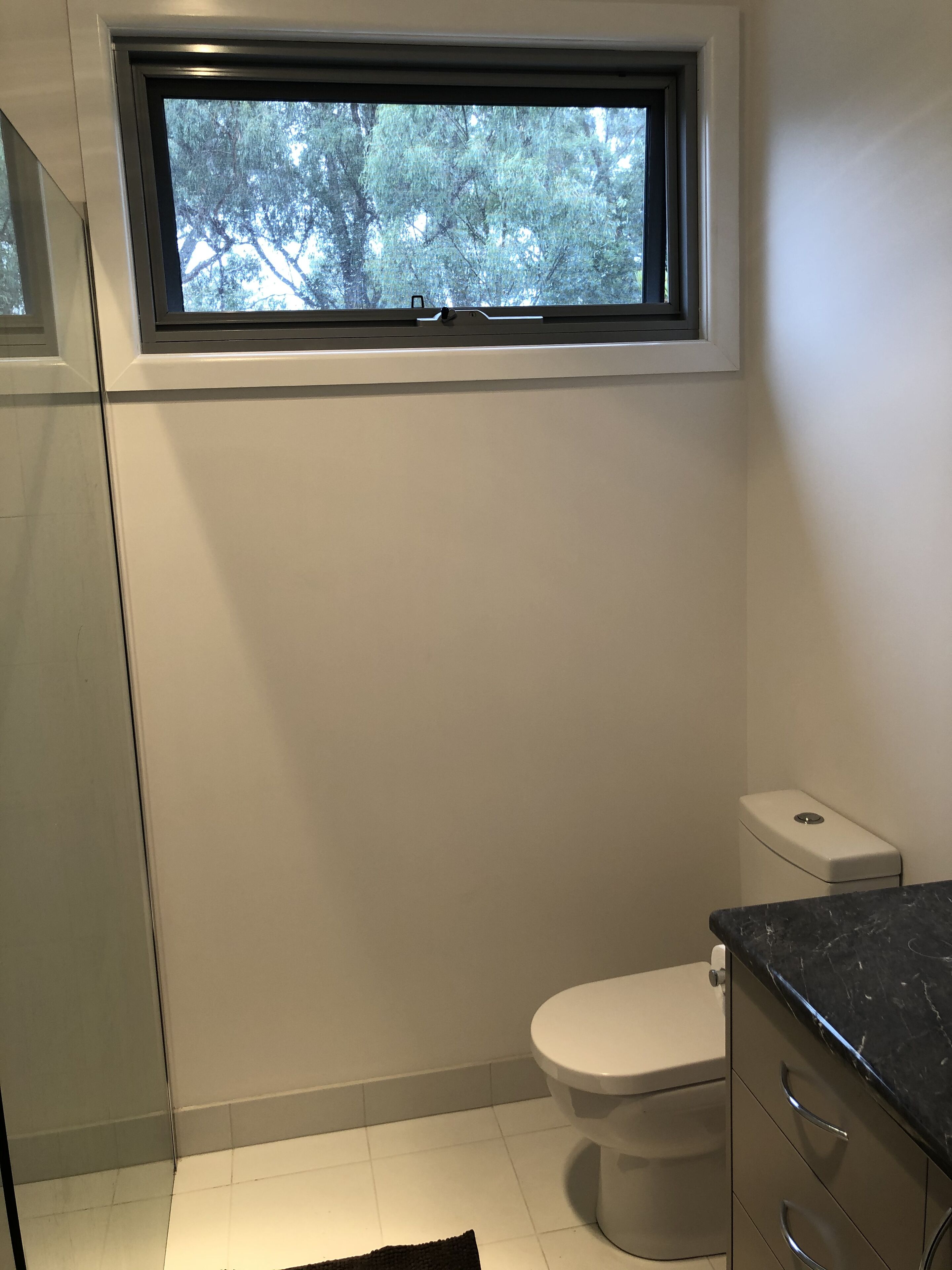 A bathroom with a toilet, a window, and a sink.