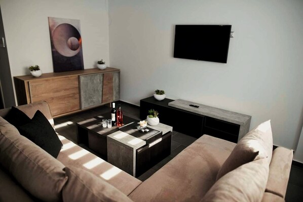 A modern living room with a sofa, coffee table, and a flat-screen TV mounted on the wall.