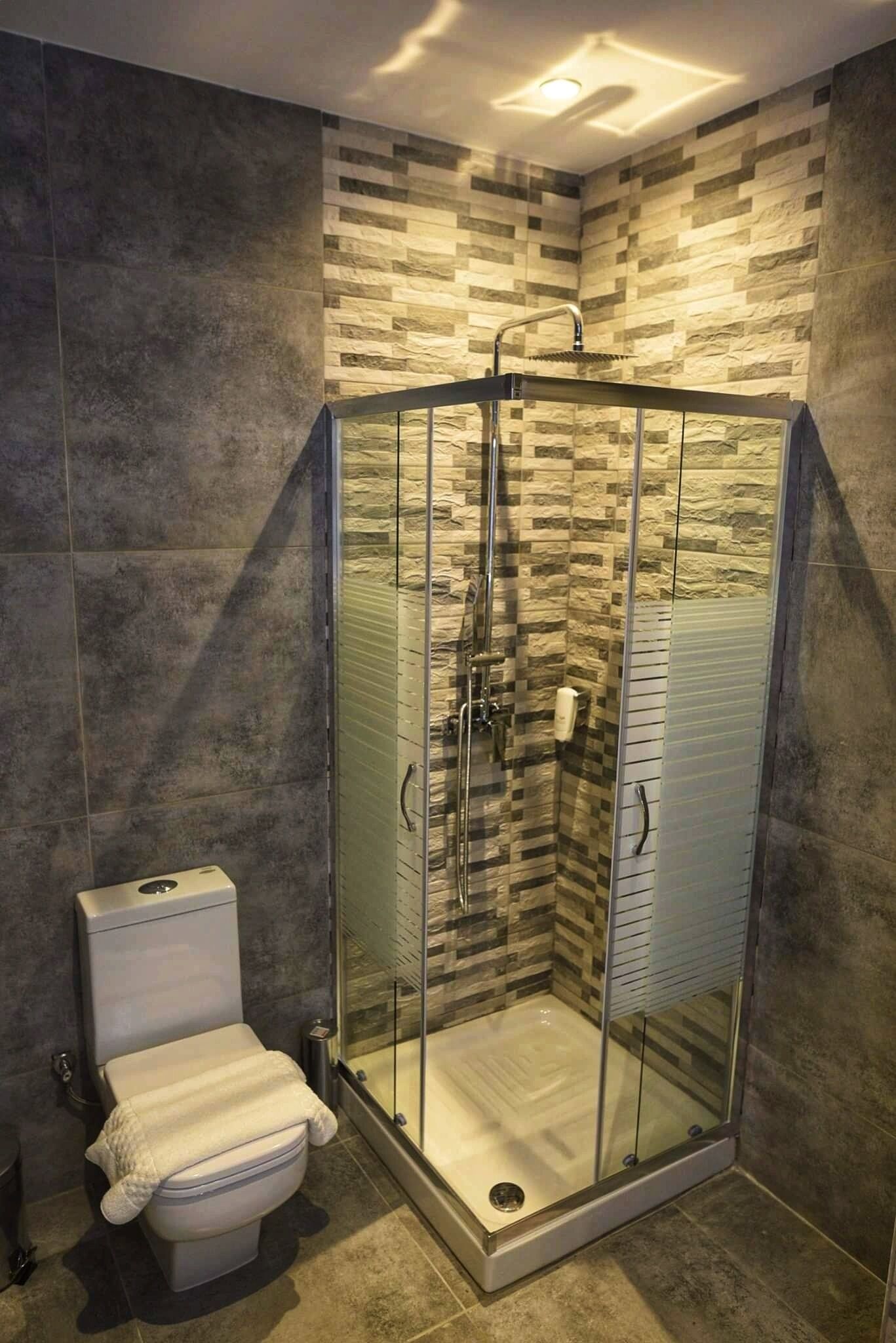 A modern bathroom with a glass-enclosed shower, a toilet, and a tiled floor.