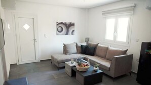 Un salon moderne avec un canapé gris, une table basse sur laquelle on a posé des fruits et un tableau accroché au mur.