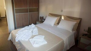 Une chambre d’hôtel avec un grand lit, une armoire en bois, une table de chevet avec une lampe et une prise de courant.