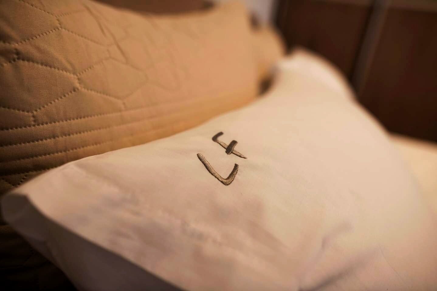 A pillow with a simple drawing of a face on a bed.