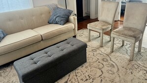 A living room with a beige sofa, a grey ottoman, two armchairs, and a patterned rug. - Home Town Getaway - 2 bed 1 bath home - close to town! (Paris)