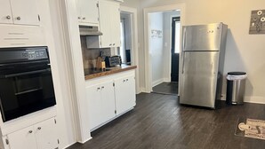 A modern kitchen with white cabinets, a stainless steel refrigerator, and a black oven. - Home Town Getaway - 2 bed 1 bath home - close to town! (Paris)
