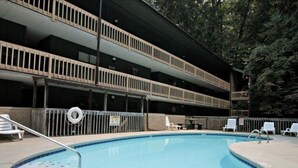 Ein Schwimmbecken mit einem dreistufigen Zugang, umgeben von einem Zaun und Liegestühlen.