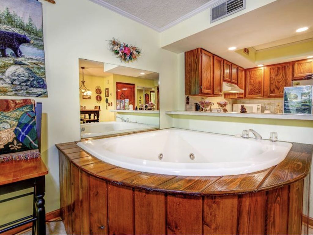 Une salle de bain avec une grande baignoire en bois, des meubles en bois et un miroir.