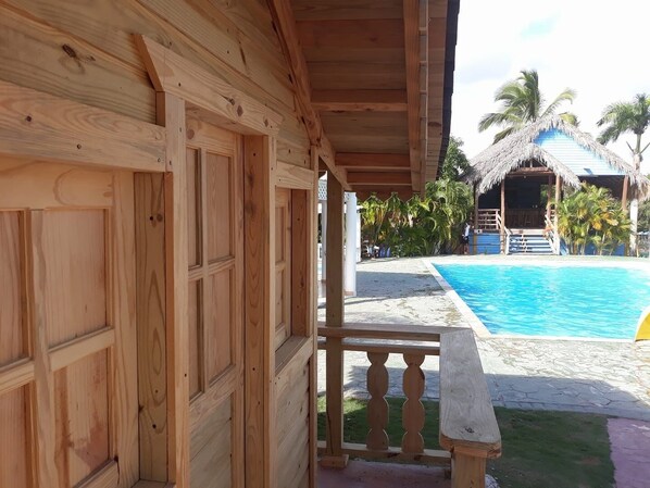 Un edificio de madera con un balcón que da a una zona de piscina.