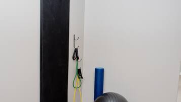 Una habitación pequeña y privada con una pared para ejercicios en color negro, una pelota de ejercicios azul y una esterilla de yoga.
