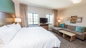 Ein Hotelzimmer mit einem großen Bett, einem Fernseher, einer Couch und einem kleinen Tisch.