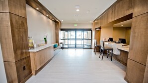 A modern hotel lobby with a reception desk, seating area, and a view of the outside. - Accessible Studio Suite, 1 King with Tub (Humble)